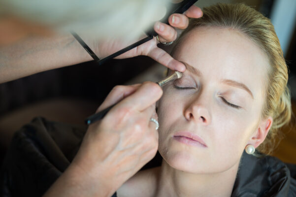 Bride having her makeup done during the wedding morning preparations in Burgundy, France.
